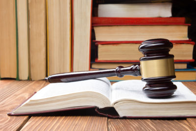 Law concept - Law book with a wooden judges gavel on table in a courtroom or law enforcement office